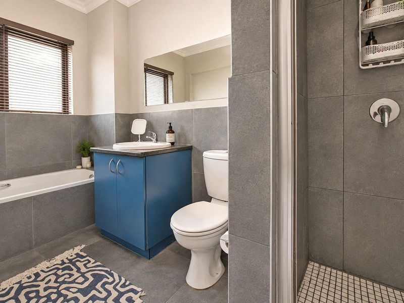 Modern bathroom featuring a built-in vanity, separate bathtub, and a tiled shower enclosure with neutral grey finishes.