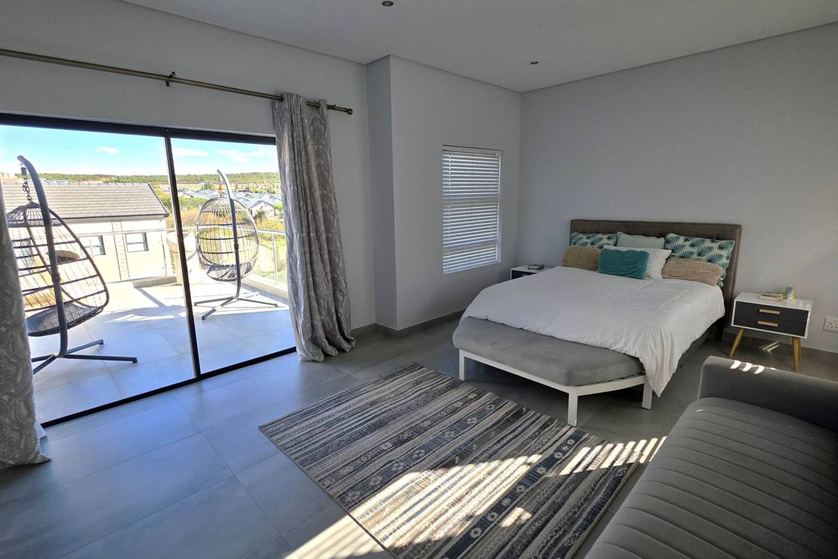Spacious bedroom featuring large sliding glass doors that open onto a private balcony with scenic views and modern tiled flooring.