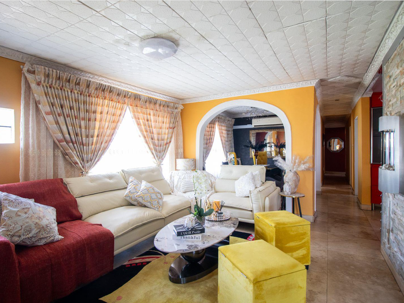 A living room featuring tiled flooring, a stone accent wall, and an arched entryway leading to an adjacent space with a ceiling-mounted air conditioning unit.