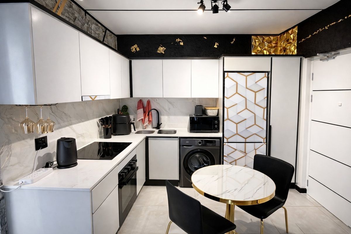 Modern kitchen featuring white cabinetry, marble-effect countertops, integrated appliances, and stylish black accents with contemporary track lighting.