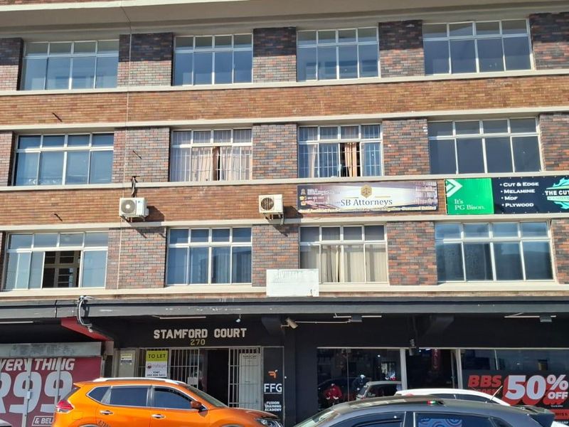 Multi-story commercial building featuring a brick facade, aluminum windows, and ground-level retail storefronts with prominent signage.