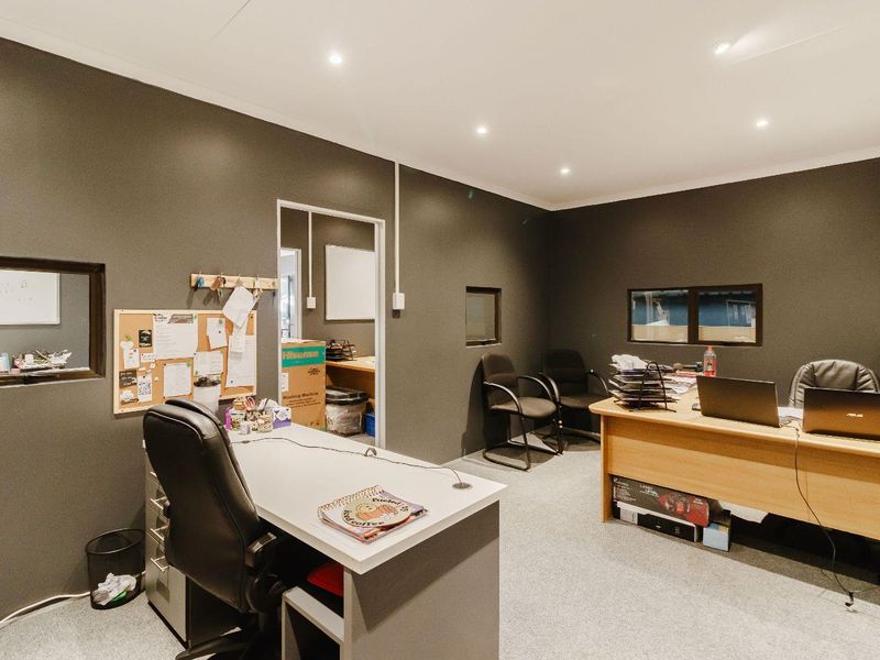 A functional office space featuring dark painted walls, recessed downlighting, and carpeted flooring, suitable for a professional commercial environment.