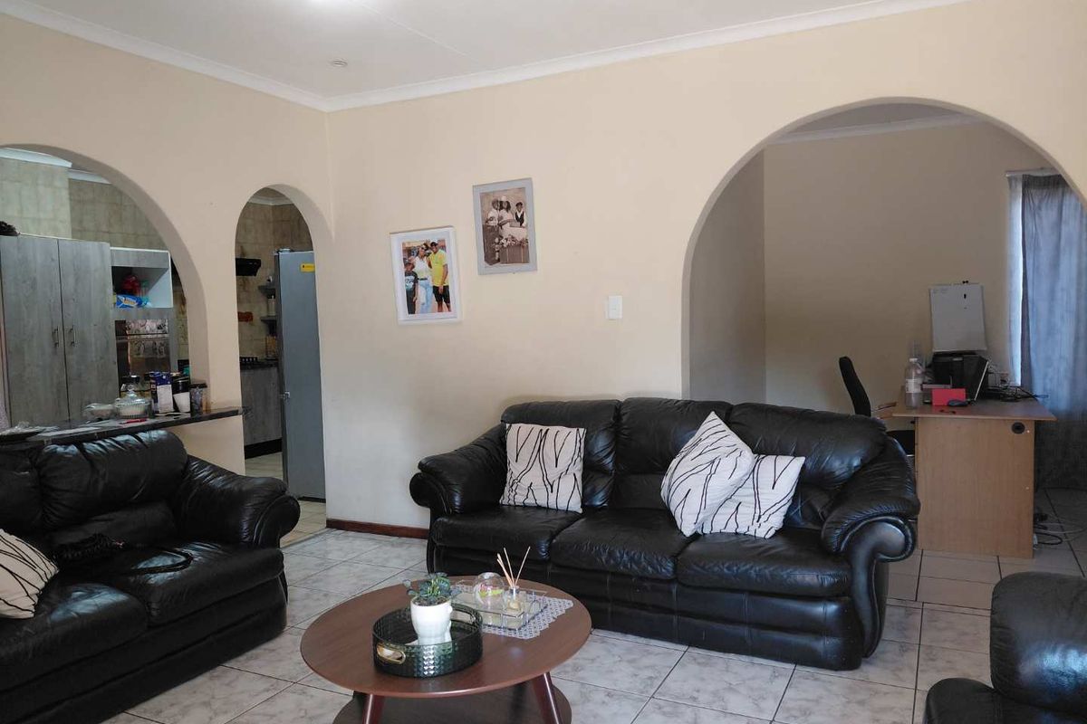 Spacious living room featuring tiled flooring and distinctive archway transitions leading to adjacent kitchen and office areas.