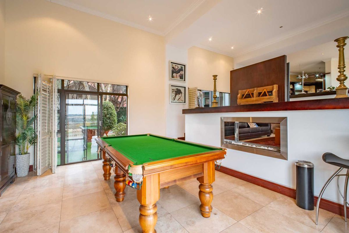 Spacious entertainment area featuring a built-in bar with a modern fireplace, tiled flooring, and large glass sliding doors leading to the outdoor patio.