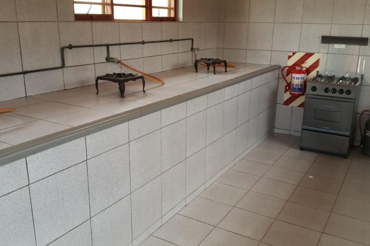 A functional commercial kitchen area featuring tiled surfaces, multiple gas burner stations, and a standalone gas stove with fire safety equipment.