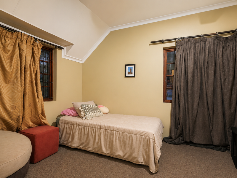 A bedroom featuring a vaulted ceiling, coved cornicing, and two windows with security bars, offering a cozy and functional living space.