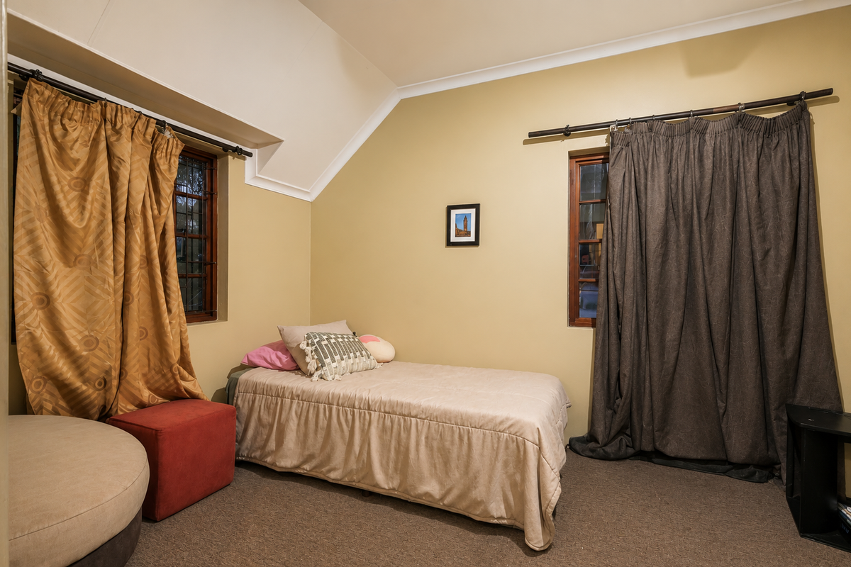 A bedroom featuring a vaulted ceiling, coved cornicing, and two windows with security bars, offering a cozy and functional living space.