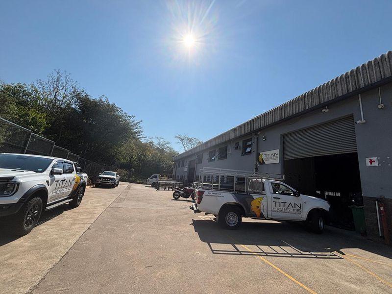 Industrial property exterior featuring a concrete yard area and a large roller shutter door access point.