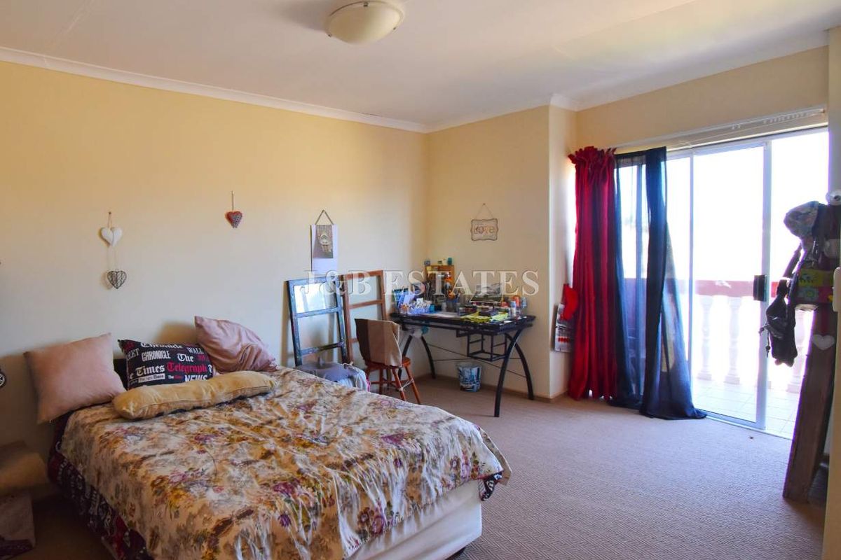 Spacious bedroom featuring neutral walls, carpeted flooring, and sliding glass doors providing direct access to an outdoor balcony area.