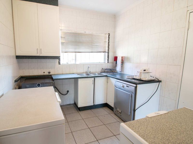 Functional laundry room featuring tiled walls, tiled flooring, built-in cabinetry, and a double basin sink with laminate countertops.