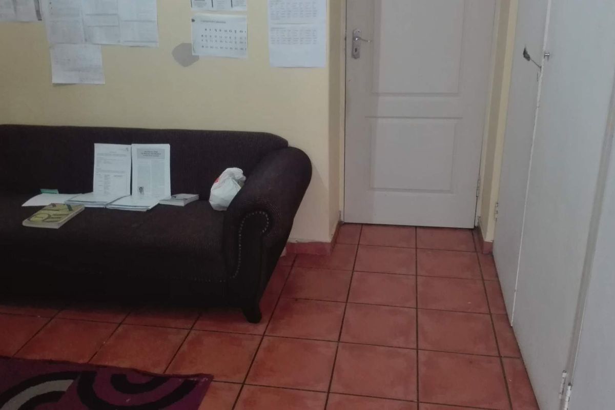 A living area featuring terracotta-style floor tiles and a built-in cupboard, currently showing signs of wear and requiring cosmetic updates.