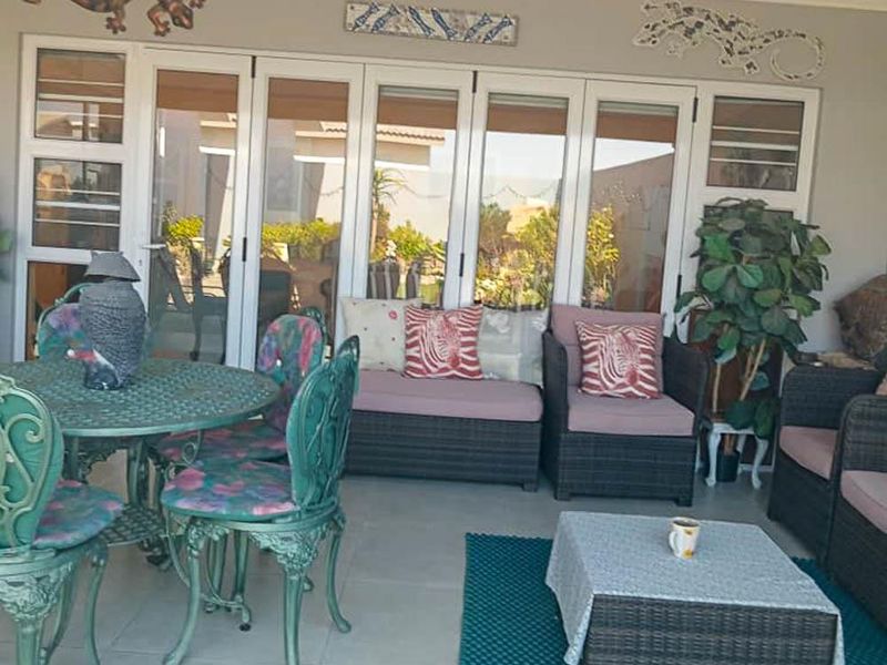 A covered patio area featuring tiled flooring and large white aluminium folding doors providing access to the interior living space.