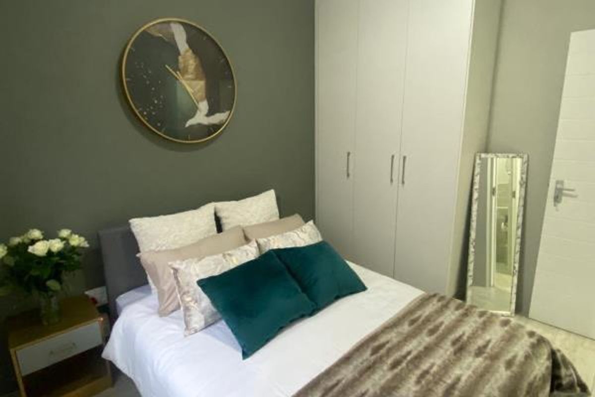 A well-maintained bedroom featuring a neutral color palette, built-in wardrobe storage, and a clean, modern aesthetic.