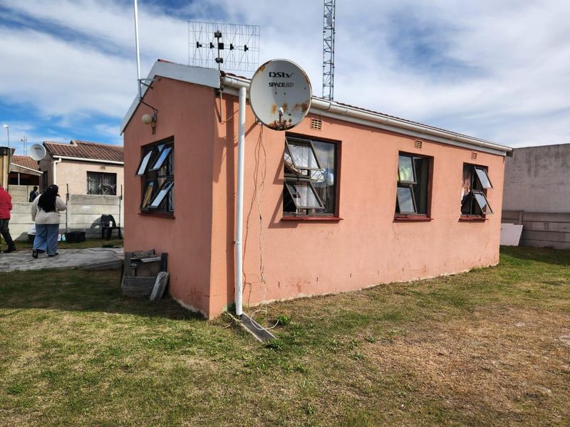 Rear view of a detached residential structure featuring plastered walls, top-hung windows, and an installed satellite dish.