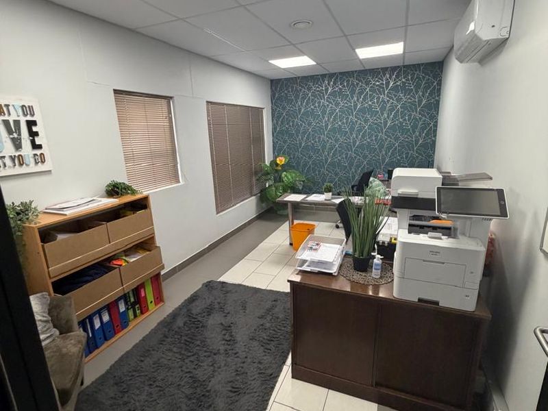 A functional office space featuring tiled flooring, recessed ceiling lighting, a split-system air conditioner, and a decorative feature wall.