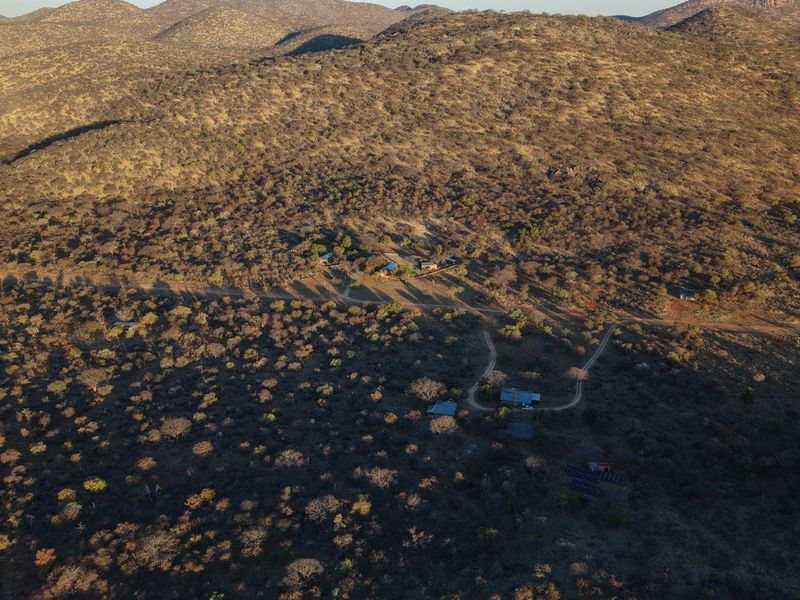 Aerial view of the lodge property situated in a vast, arid landscape, featuring multiple structures, gravel access roads, and a solar panel array.