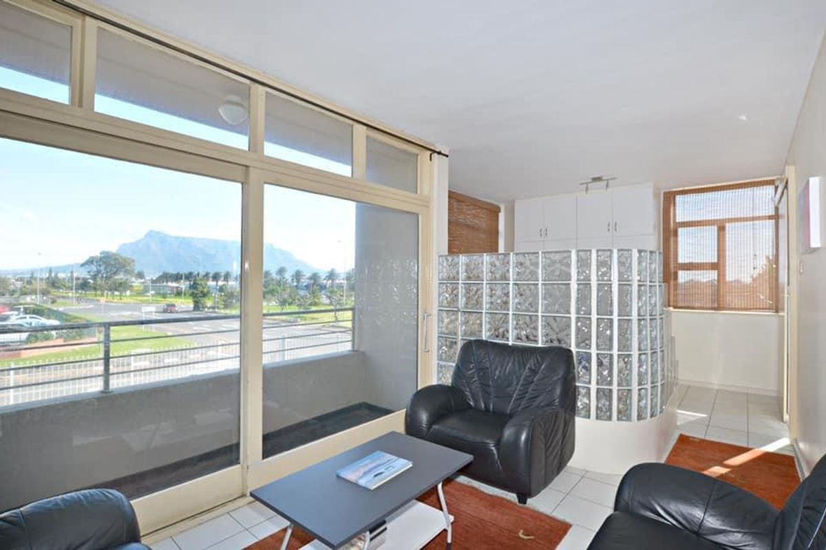 Living area featuring large sliding glass doors with mountain views, tiled flooring, and a distinctive glass block partition wall with built-in storage.