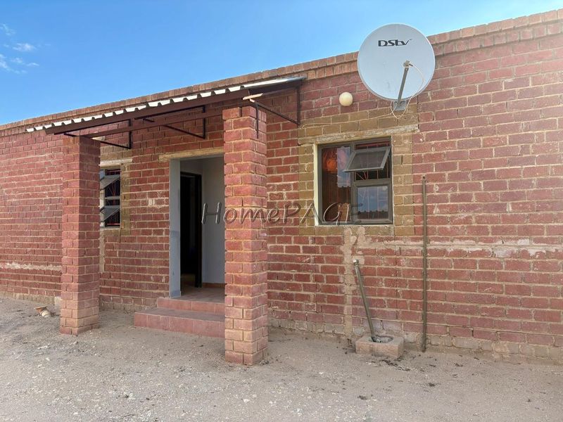 Front exterior view of a house featuring exposed brick walls, brick support pillars, a metal awning over the entrance, and a satellite dish.