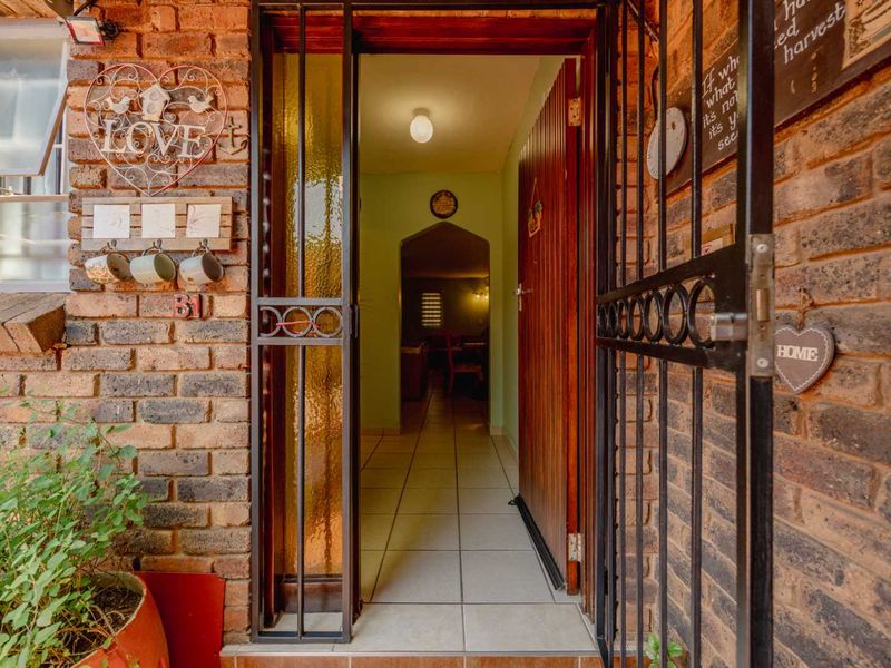 Entrance area featuring a secure metal gate, brick exterior facade, and tiled flooring leading into the home interior.
