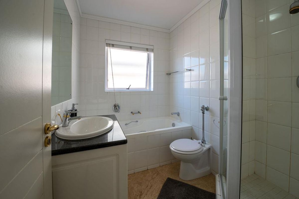 A functional bathroom featuring a built-in bathtub, separate shower enclosure, and a vanity with a granite countertop.