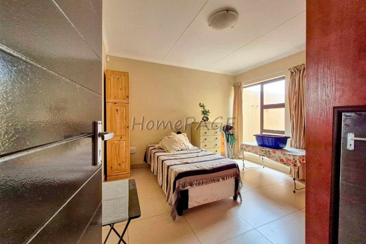 A standard bedroom featuring tiled flooring, neutral wall finishes, and a window providing natural light.