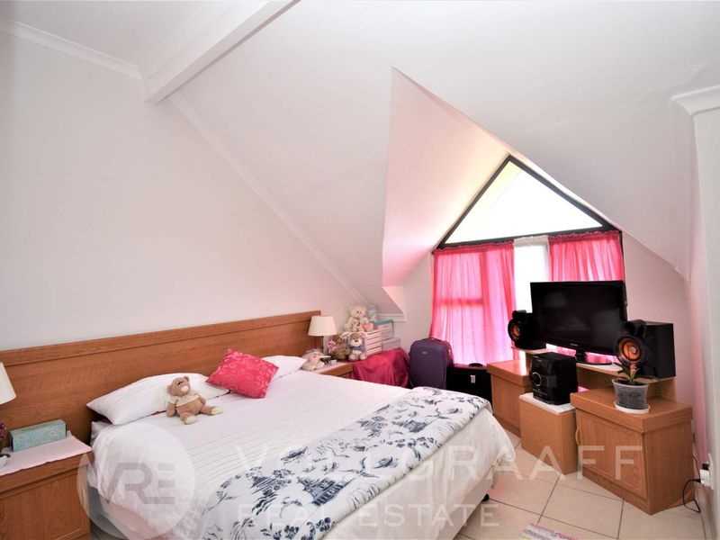 A bedroom featuring a unique pitched ceiling with a triangular window, providing natural light and architectural character to the space.