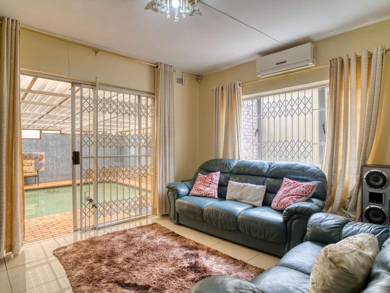 A living room featuring tiled flooring, a split-system air conditioner, and sliding glass doors providing direct access to an indoor pool area.