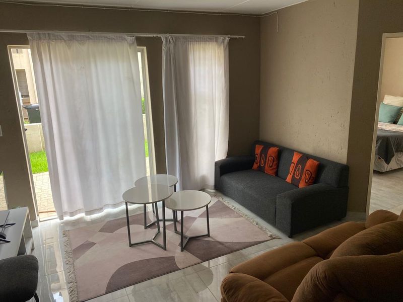 A living room featuring tiled flooring and a sliding glass door providing access to an outdoor area.