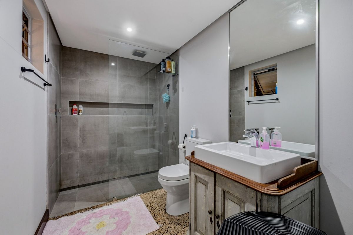 Modern bathroom featuring a walk-in shower with grey tiling, a vessel sink vanity, and a large wall mirror.