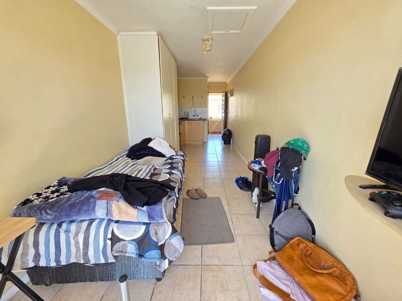 Open-plan studio apartment featuring tiled flooring, built-in wardrobe, and a compact kitchen area with sink and cabinetry.