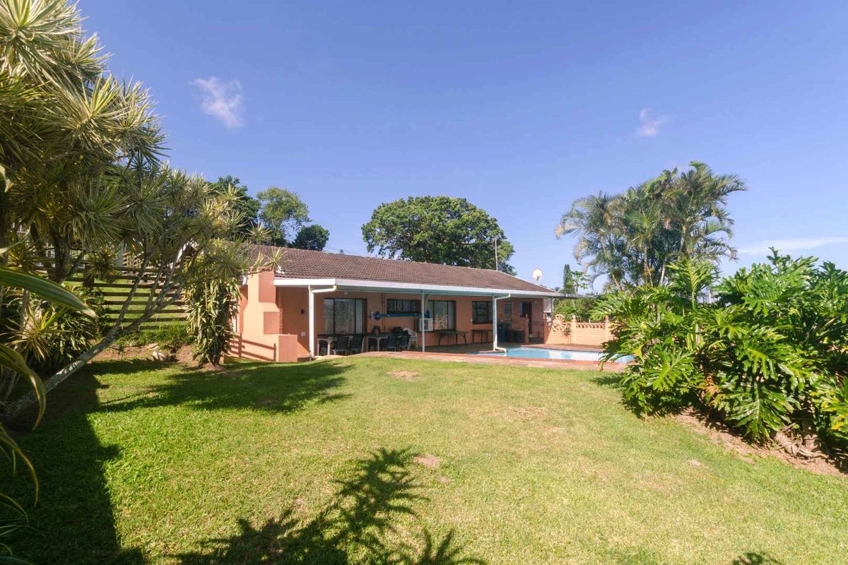 Rear view of the house featuring a covered patio, swimming pool, and a spacious landscaped garden area.