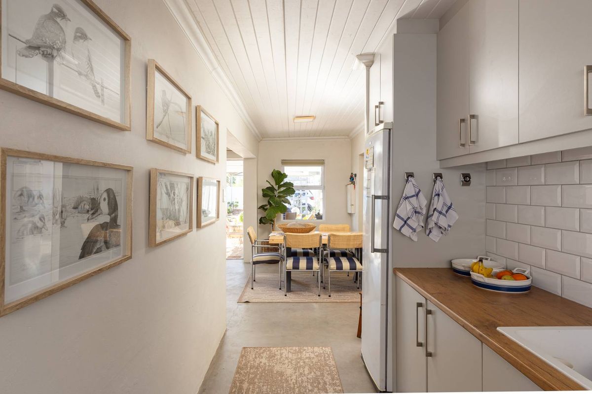 A bright kitchen featuring modern cabinetry, subway tile backsplash, and wood-look countertops, leading into a dining area with natural light.