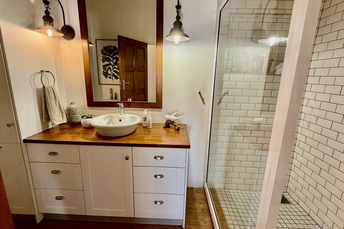 A well-appointed bathroom featuring a wooden vanity with a vessel sink, a framed mirror, and a walk-in shower with classic white subway tiling.