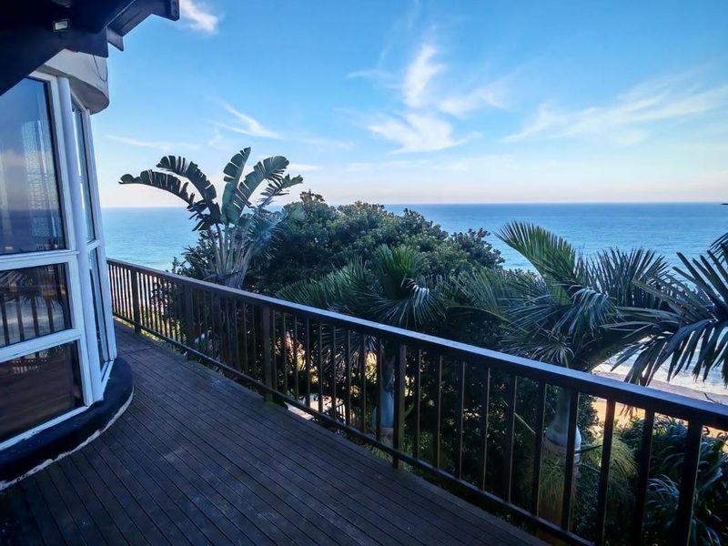 Spacious elevated balcony featuring timber decking and balustrades, offering expansive ocean views and a peaceful outdoor setting.