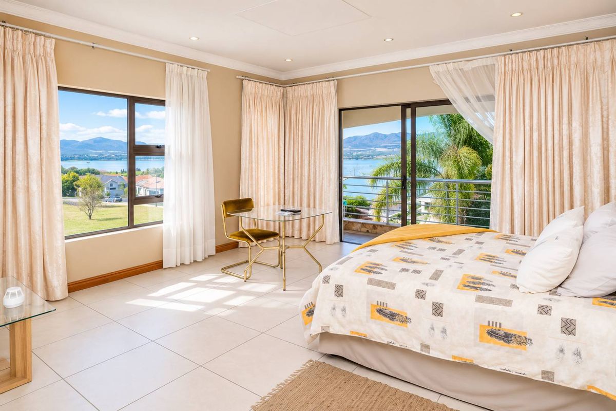 Spacious bedroom featuring tiled flooring, recessed lighting, and sliding glass doors opening onto a balcony with scenic water and mountain views.