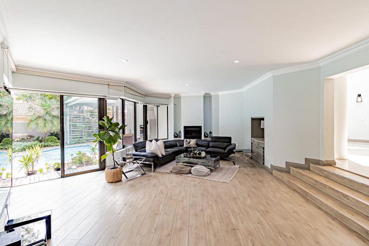 Spacious living room featuring light wood-look flooring, a built-in fireplace, and large sliding glass doors providing direct access to the pool area.