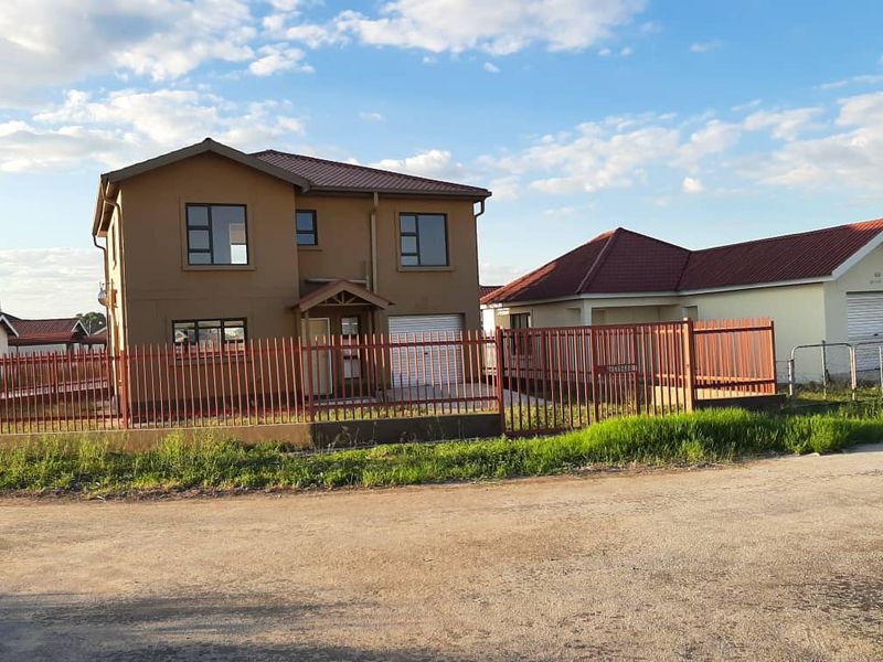 A two-storey residential house featuring a tiled roof, metal perimeter fencing, and a garage, situated in a suburban neighborhood setting.
