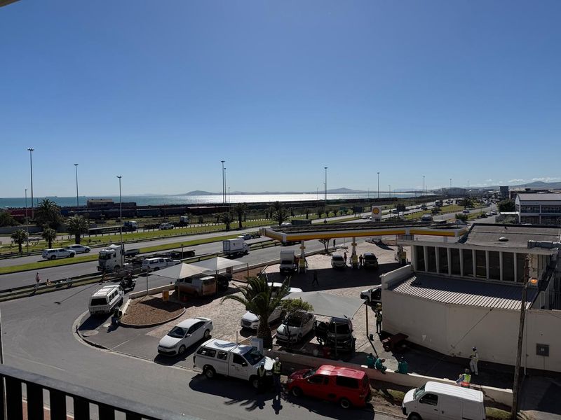 An elevated view overlooking a coastal road, a petrol station, and the distant ocean horizon.
