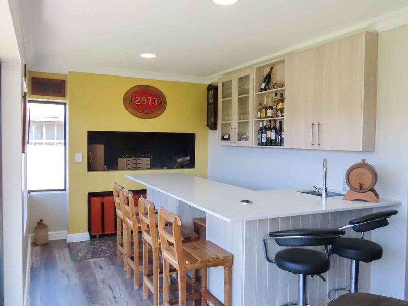 A well-appointed indoor bar area featuring a built-in counter, cabinetry, sink, and integrated braai, perfect for entertaining.