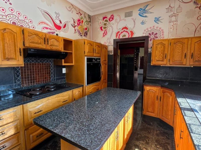 A functional kitchen featuring wooden cabinetry, granite countertops, a built-in oven, and a central island, offering a classic layout with ample storage space.