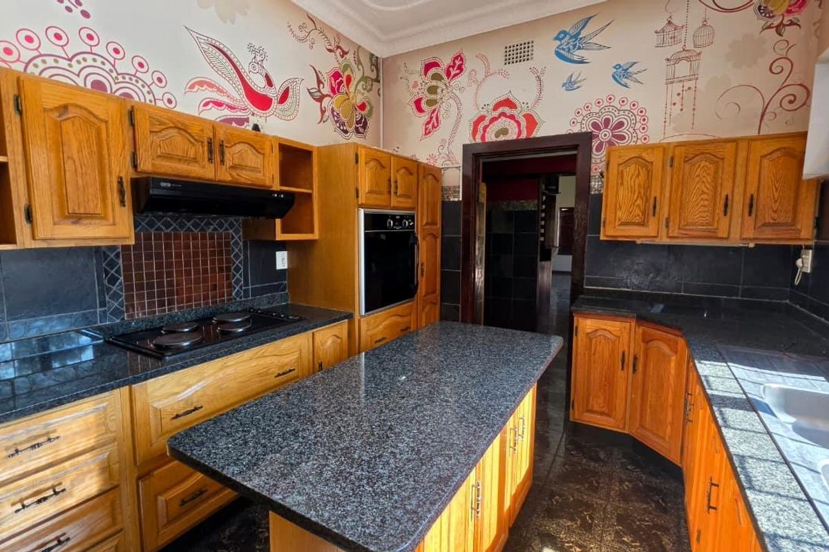 A functional kitchen featuring wooden cabinetry, granite countertops, a built-in oven, and a central island, offering a classic layout with ample storage space.