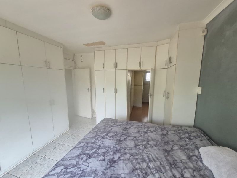 Bedroom featuring extensive built-in cupboard storage, tiled flooring, and direct access to an adjoining room.