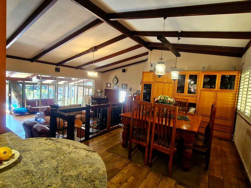 Spacious open-plan dining area featuring exposed timber beams, built-in cabinetry, and plantation shutters, seamlessly connecting to the adjacent living space.
