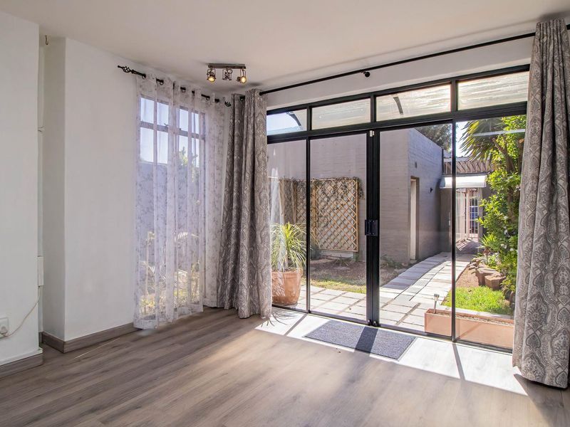 Bright living area featuring modern laminate flooring and large black-framed sliding glass doors providing direct access to the rear garden and patio.