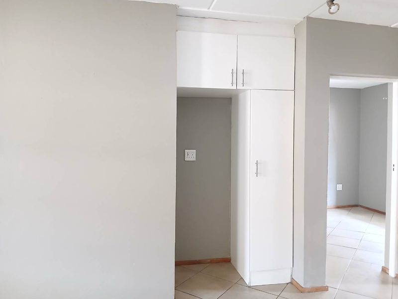 A functional kitchen area featuring built-in white cabinetry and tiled flooring, offering a clean, neutral space ready for customization.