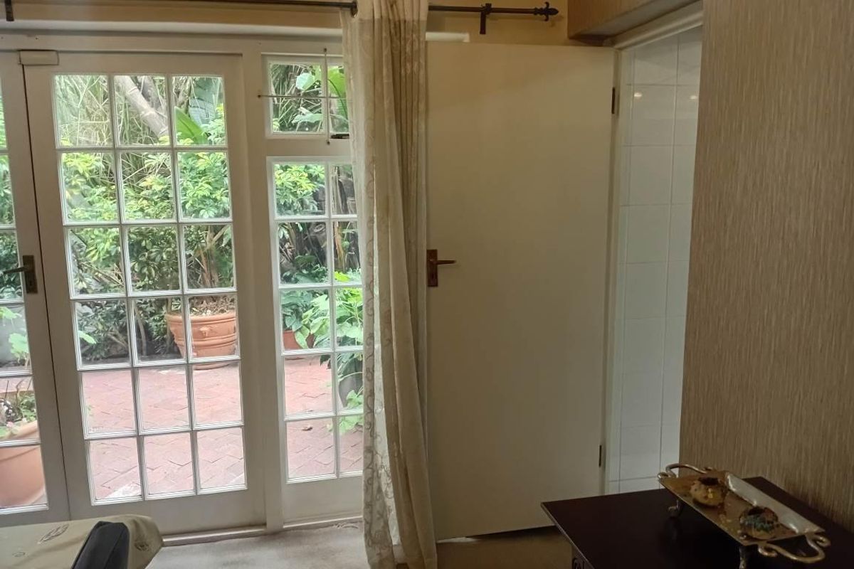 Living area featuring classic French doors that open onto a private paved patio and garden space.