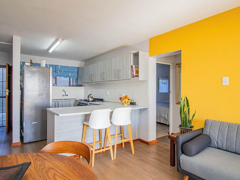 Open plan living area featuring a functional kitchen with breakfast bar, tiled flooring, and direct access to adjacent rooms.