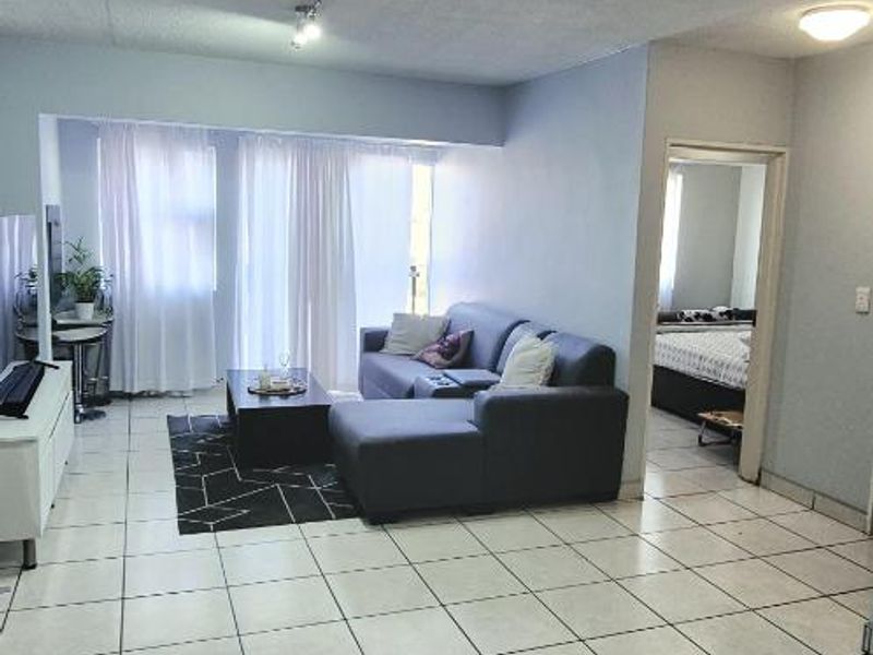 Spacious living area featuring ceramic tiled flooring, textured ceilings, and integrated track lighting, providing a functional open-plan layout.