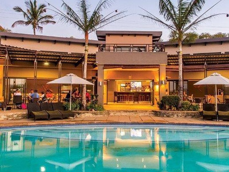 A well-maintained outdoor pool area featuring a large swimming pool, covered patio space, and integrated bar area, ideal for leisure and entertainment.