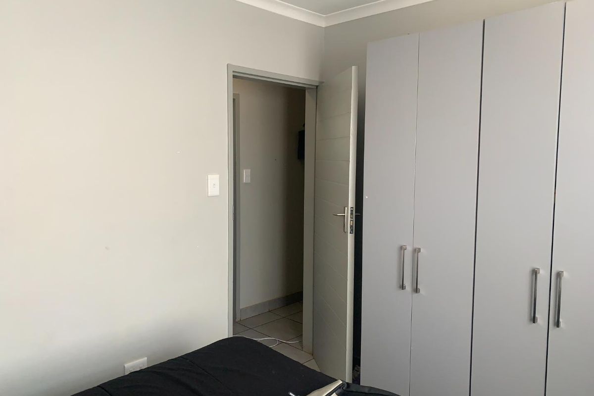 A bedroom featuring built-in cupboards with modern handles and a neutral color palette, providing clean and functional storage space.